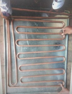 Serpentine copper coolant pipe routed on defreezer wall before paste application